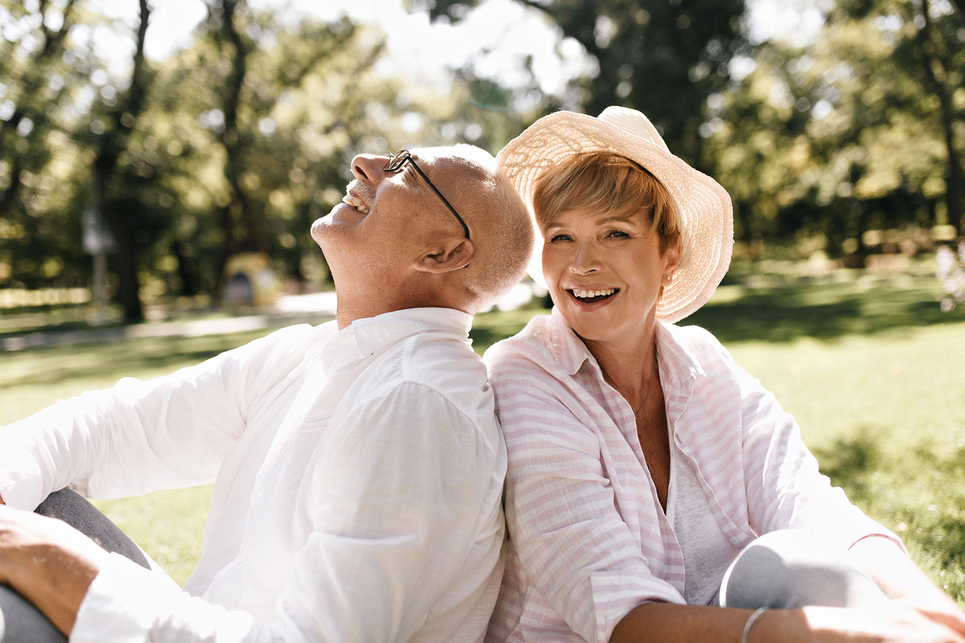 Happy older couple sits in the grass